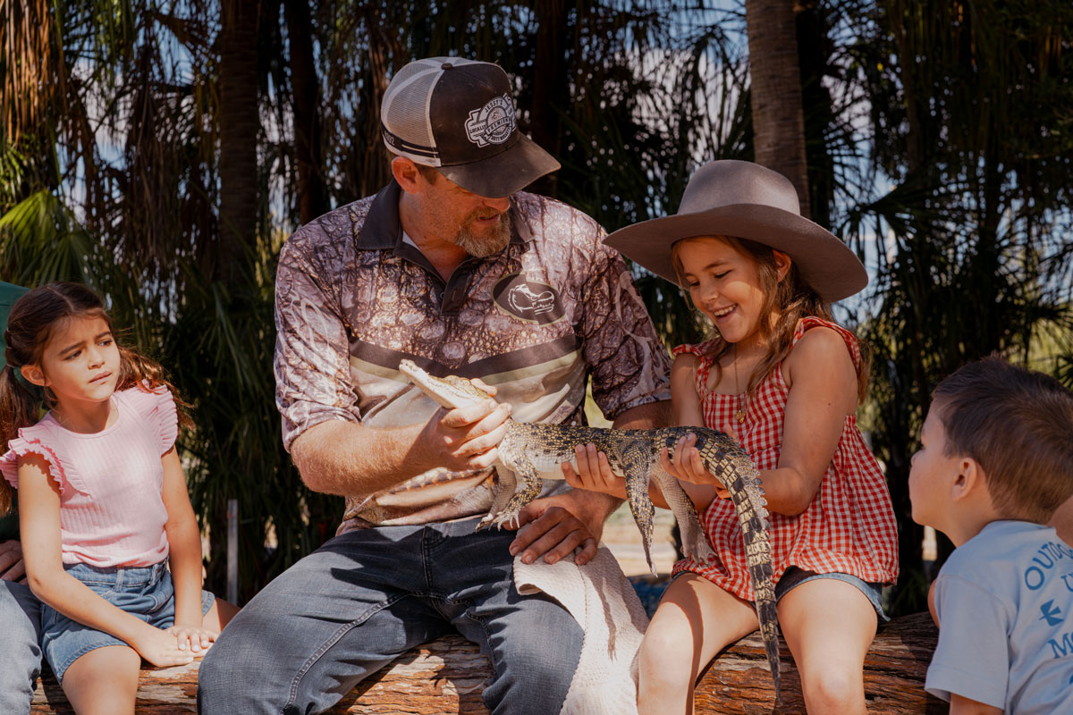 Crocodile keeper showing a crocodile to a young visitor