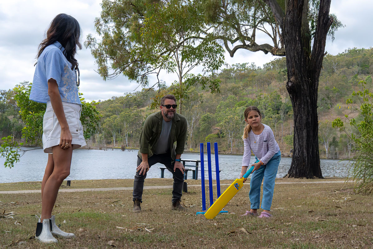 A woman, man and a child playing cricket