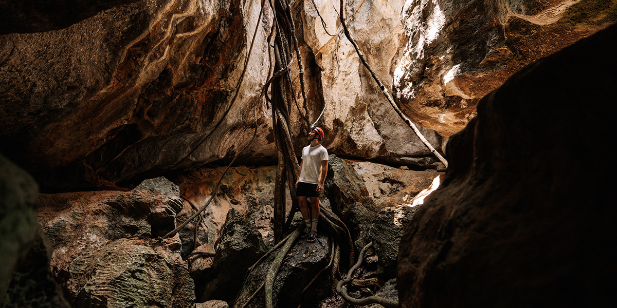 a man standing in an ancient cave with a torch helmet on