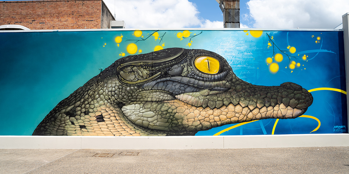 a mural on a brick wall of a crocodile
