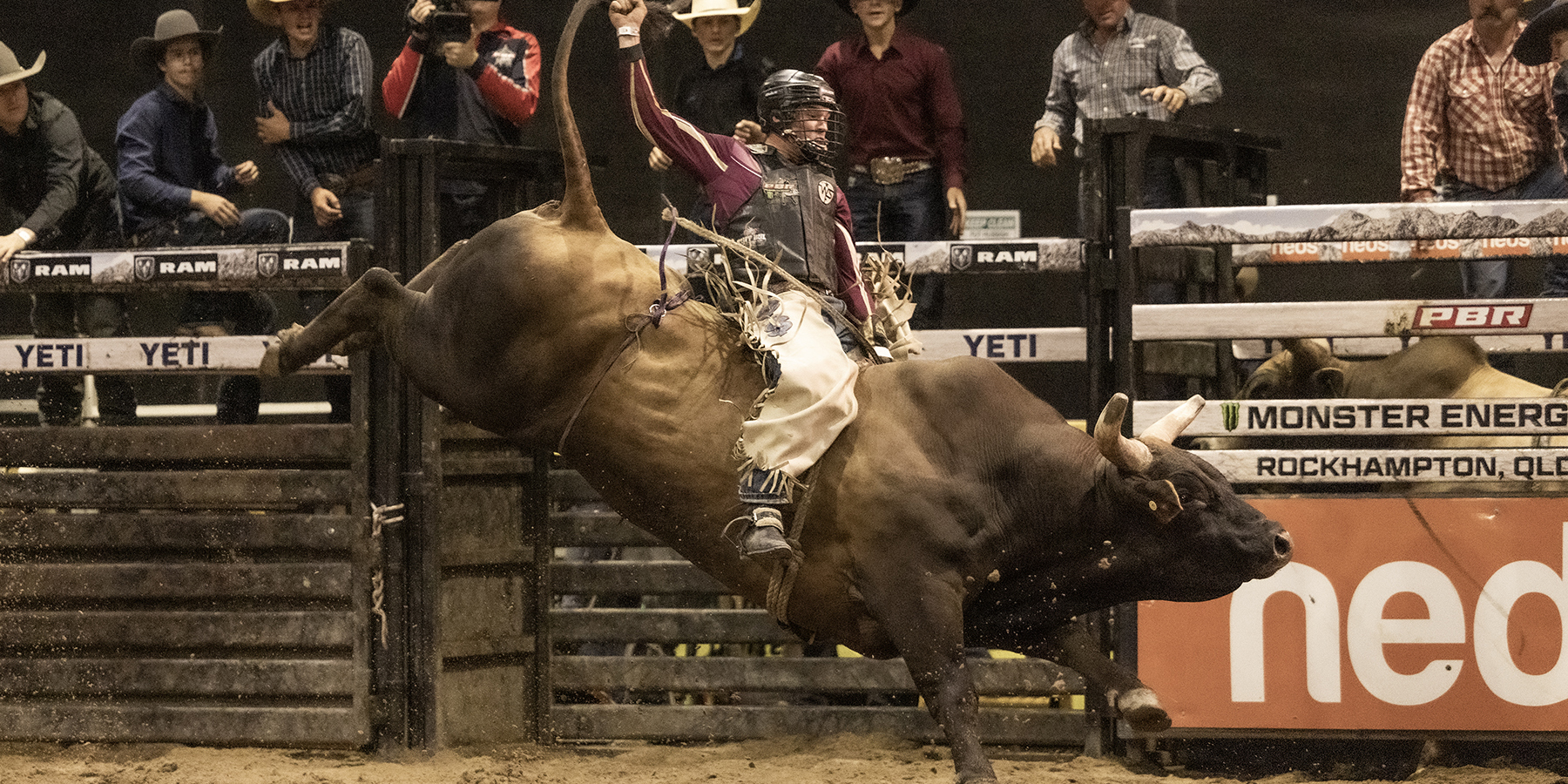 Man holding on for dear life has he gets bucked by a very energetic beast of a bull at a bull riding event.