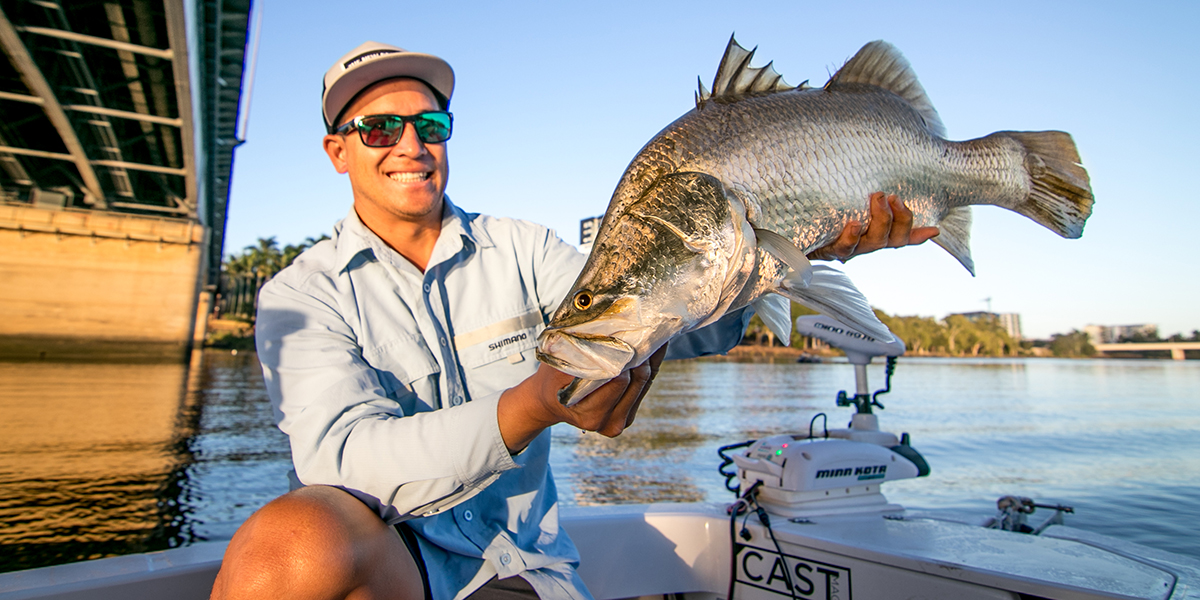 young many in a boat in the Fitzroy River smiling holding a trophy sized barramundi