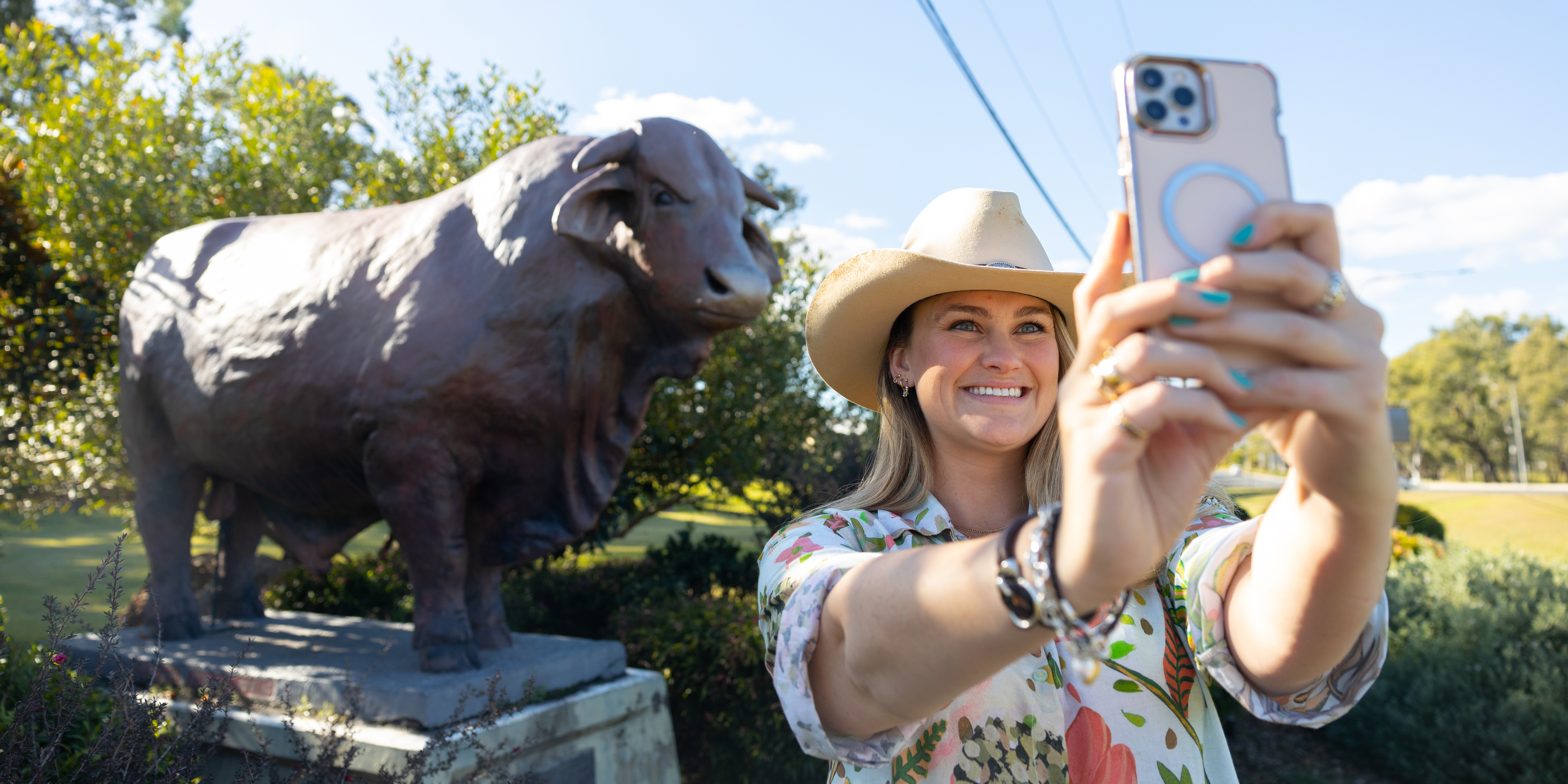 Young woman taking selfie with a Bull statue