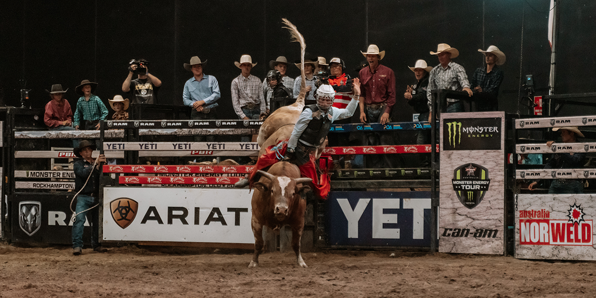 Bull rider holding on for dear life as he rides an energetic bull around the Great Western Hotel bull ring.