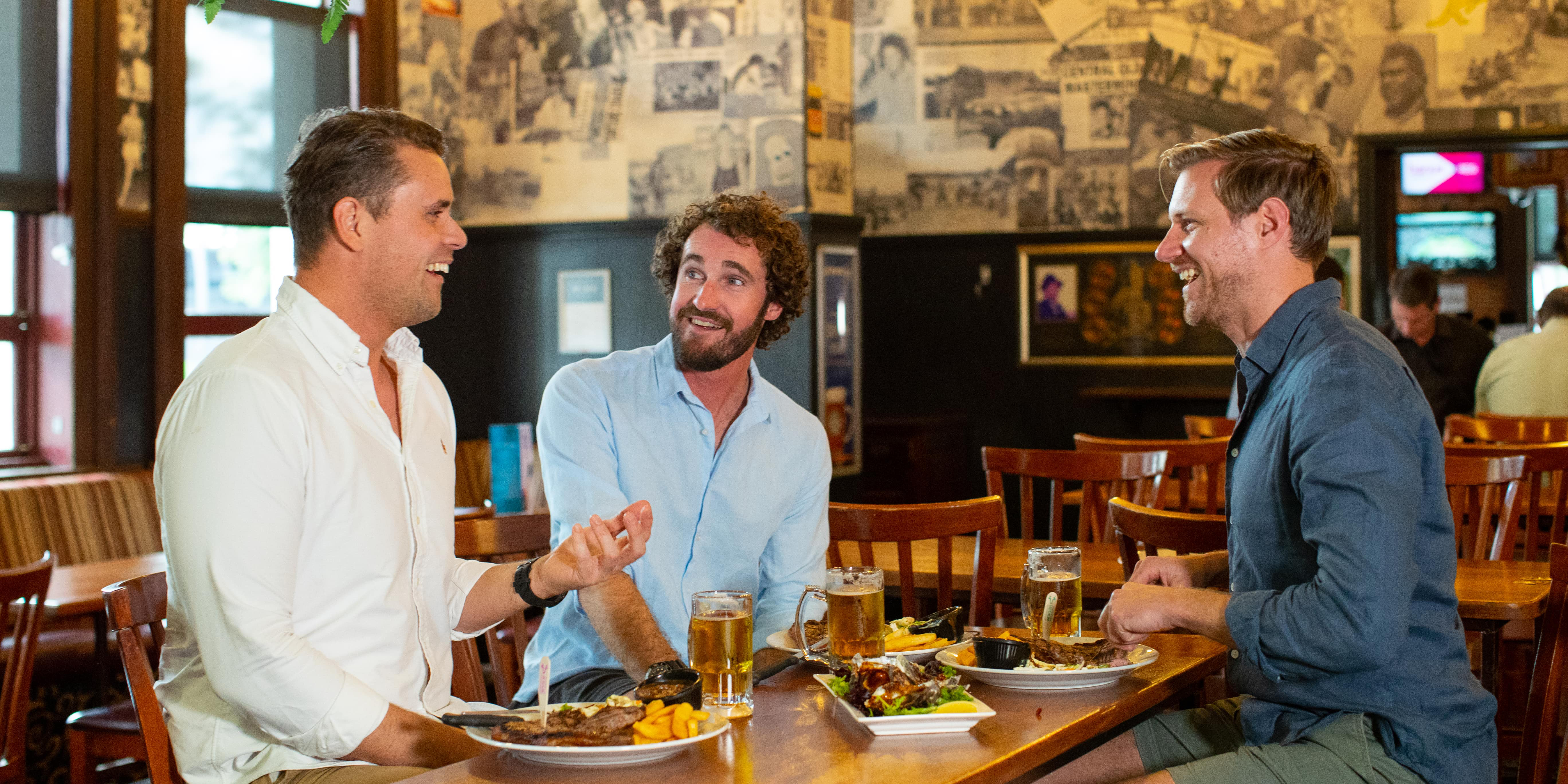 Three men sitting around a high table enjoying a pub lunch