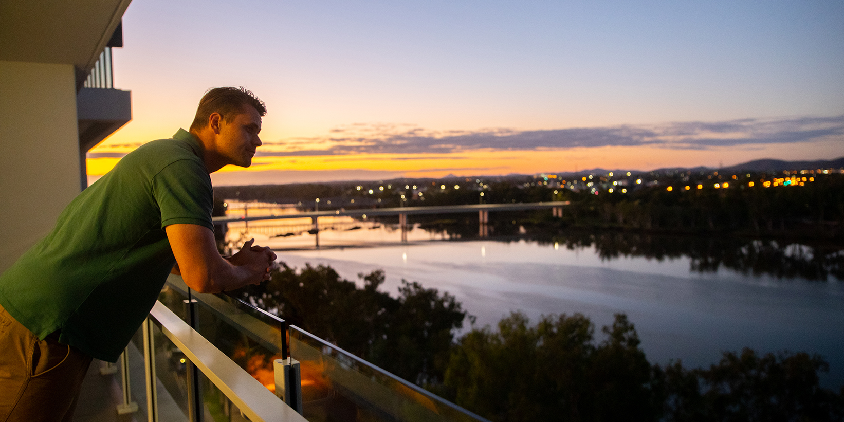 man leaning over Empire Apartment balcony