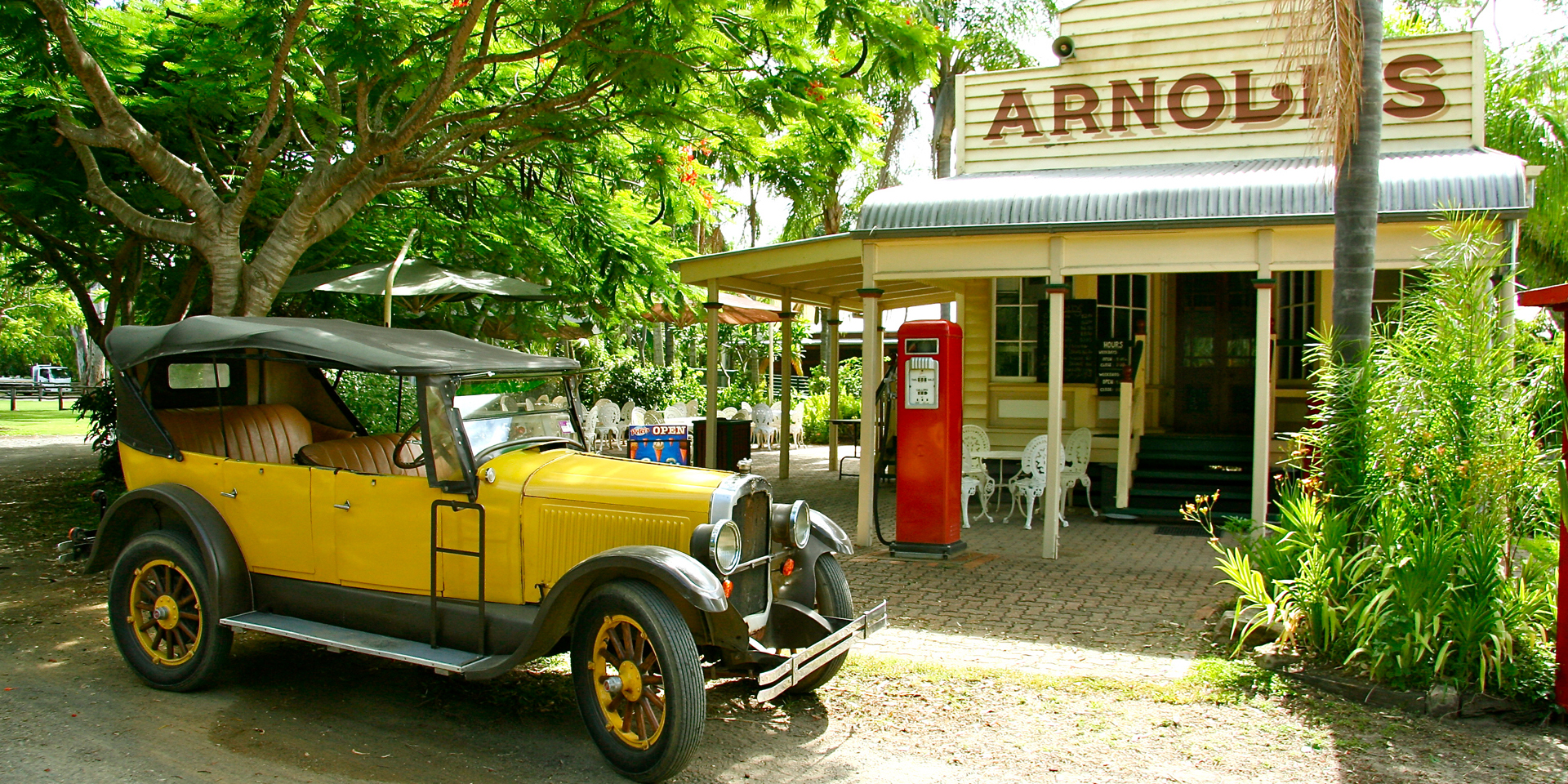 Old general store called Arnolds with a yellow vintage car parked out the front