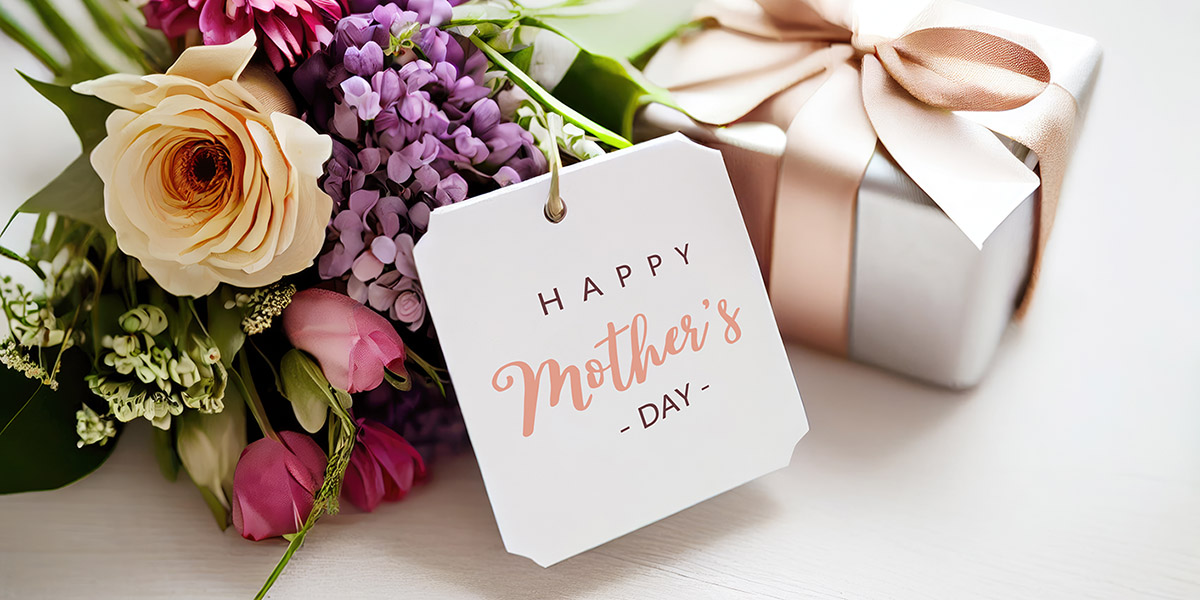 A picture of a bouquet of flowers, wrapped gift with a bow and card reading Happy Mother's Day.