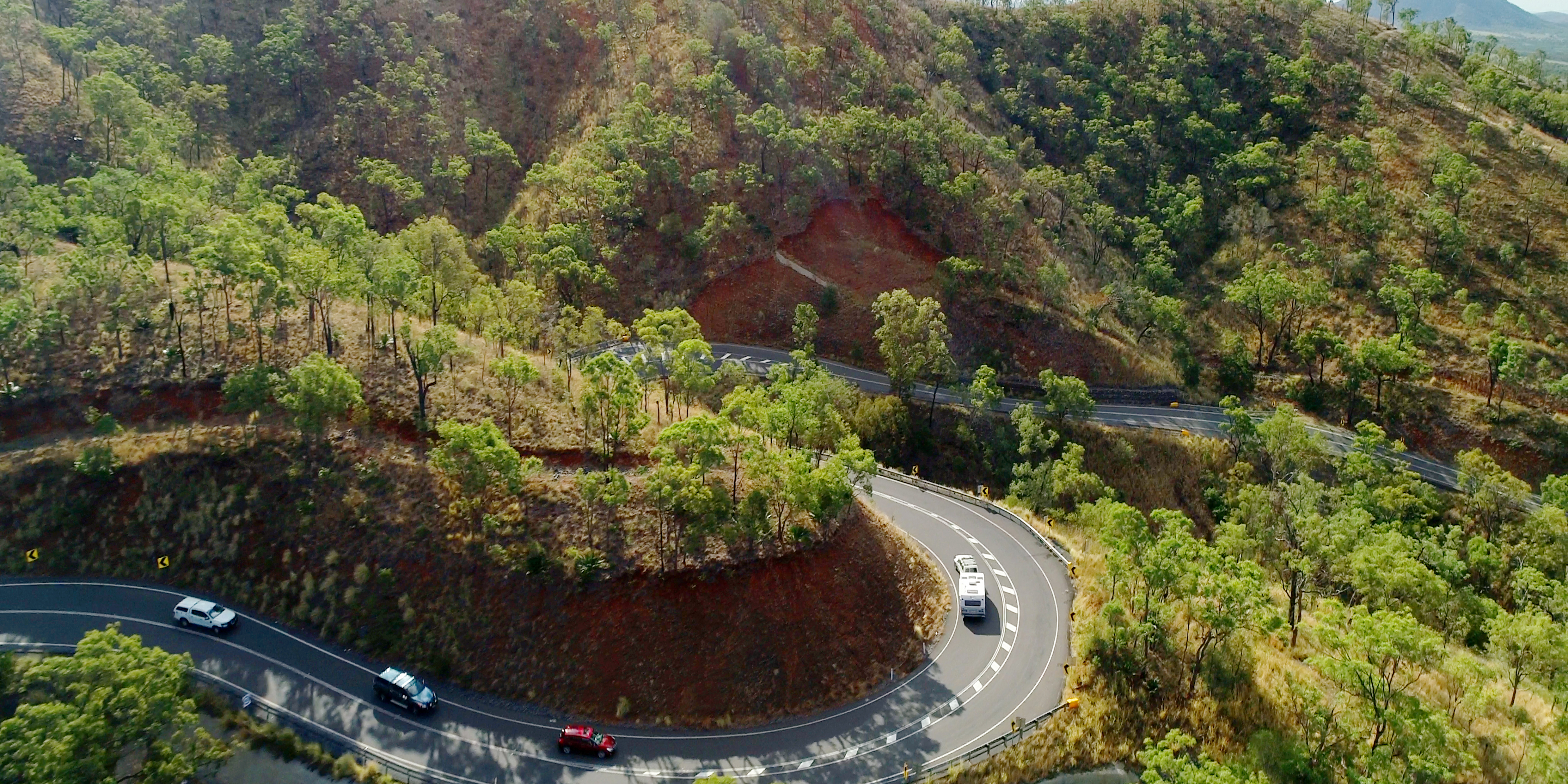 An aerial photo of a range in the hills with cars driving along a winding road.