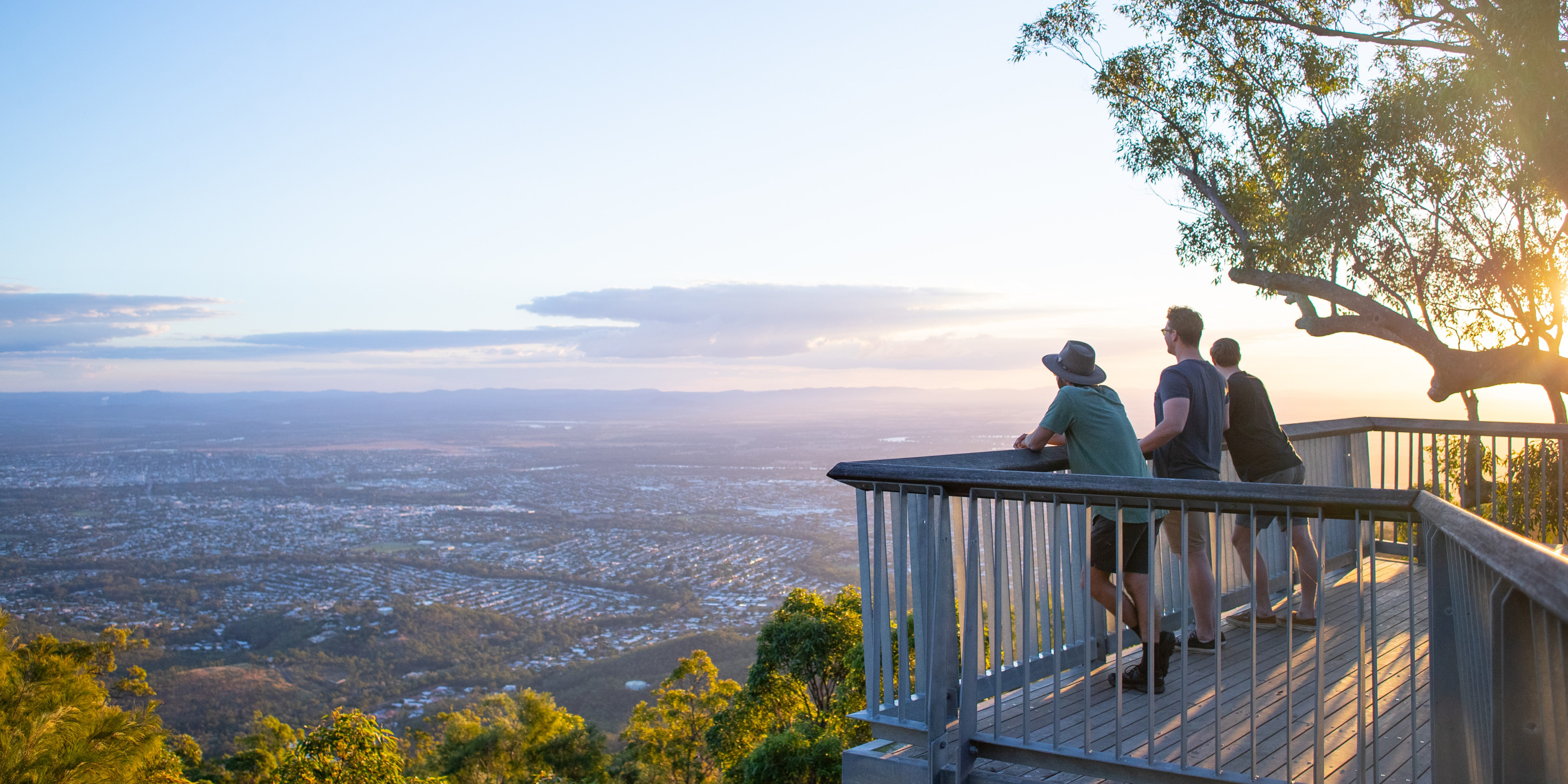 Three men looking out to a view of Rockhampton city from high up on a mountain top.