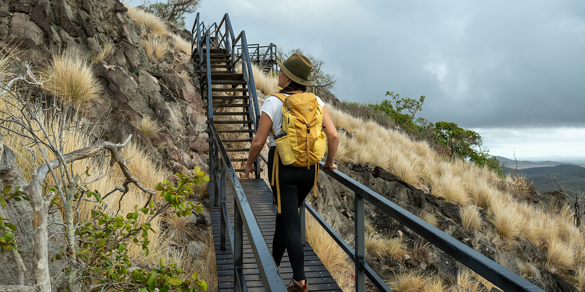 Young girl walking along a boardwalk at Mount Etna overlooking the mountainous region.