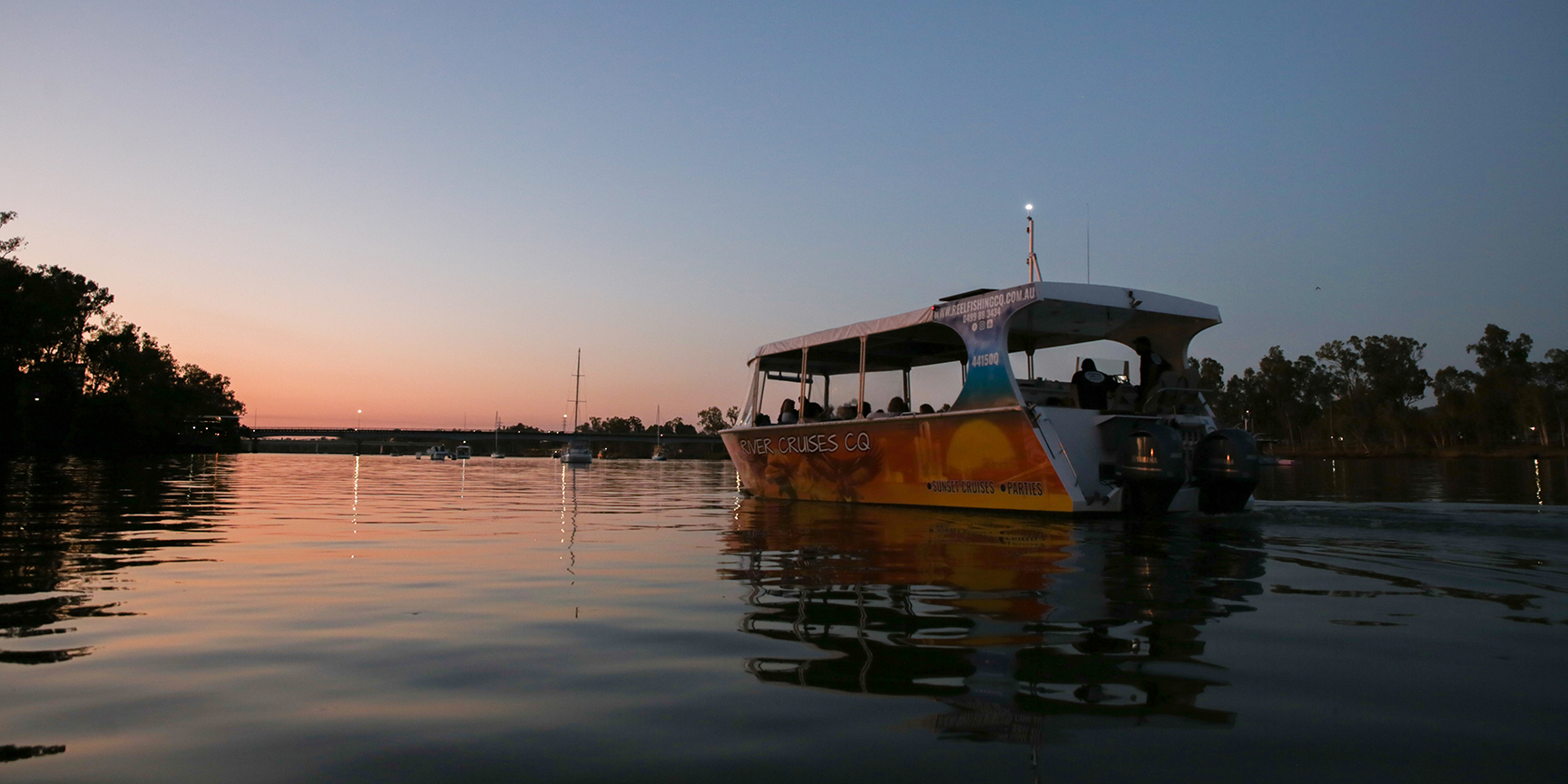Boat cruising the Fitzroy River as the sun sets on the horizon