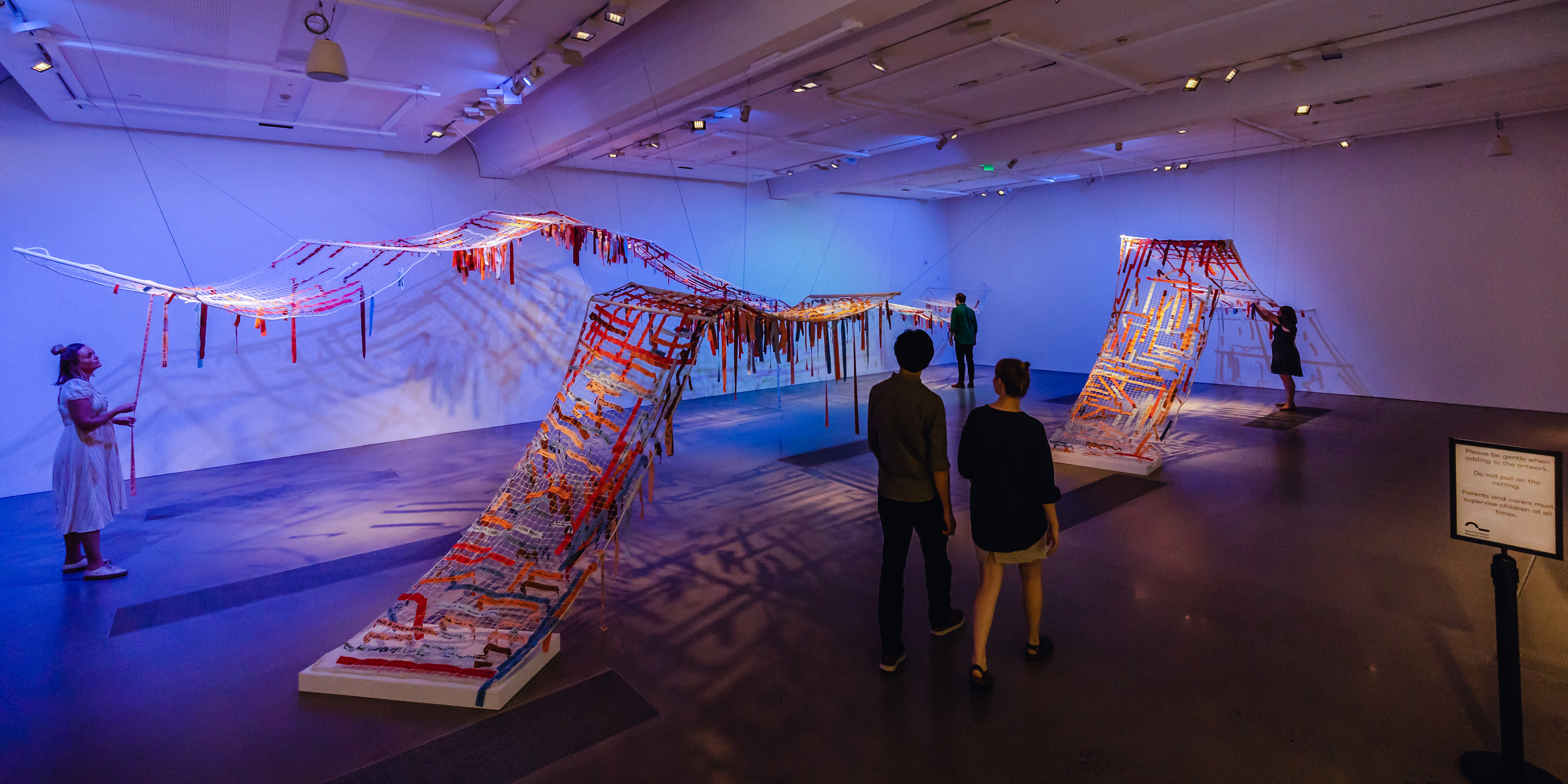 Visitors scattered throughout an exhibition at Rockhampton Museum Of Art
