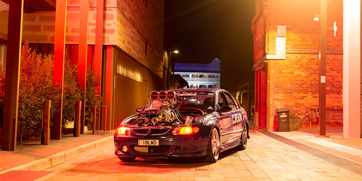 Classic car parked in an alleyway surrounded by historical buildings.