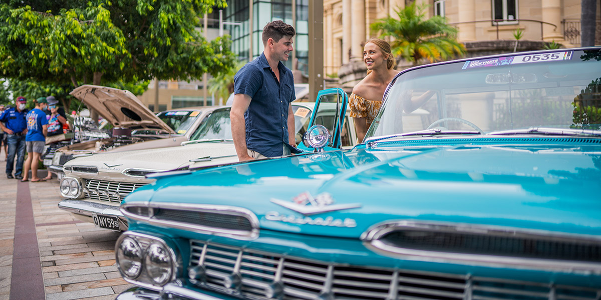 Young couple look at a classic car on the riverside precinct at rockynats.