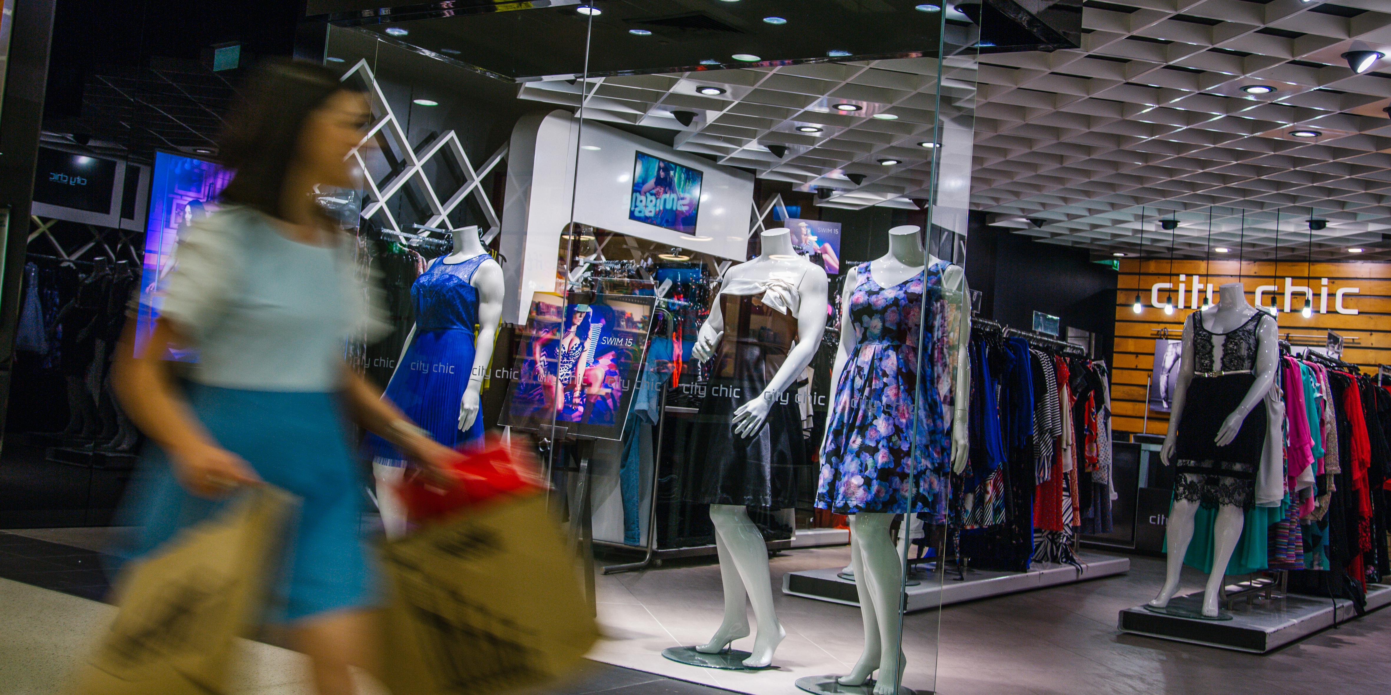 young woman carrying shopping bags in motion blur walking past a shop