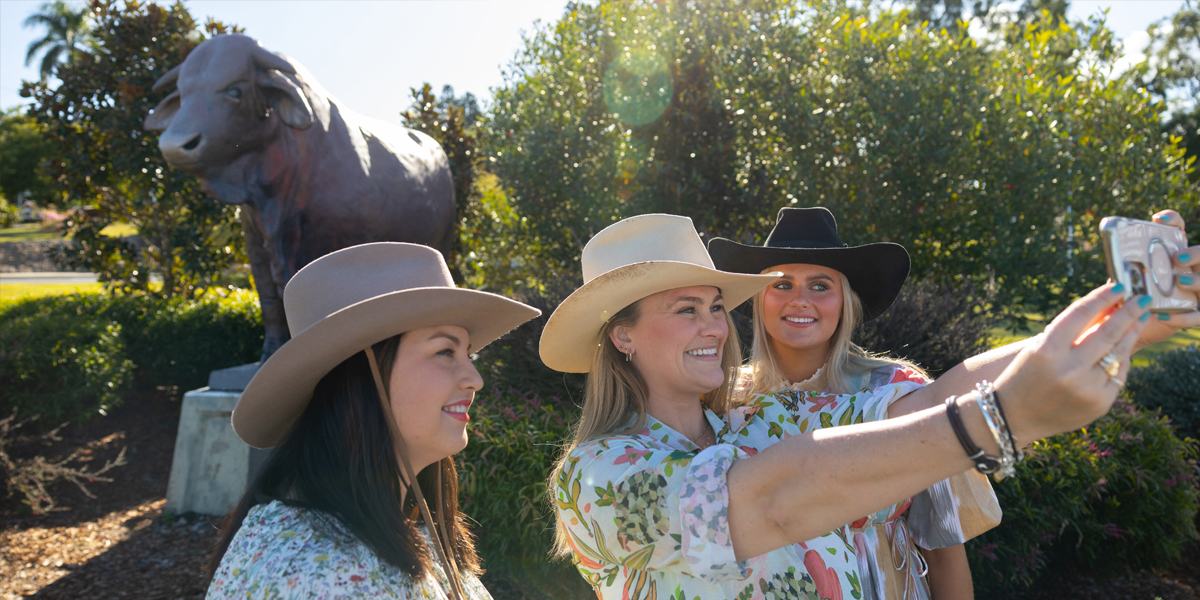 Three young women taking a selfie in front of a bull statue.