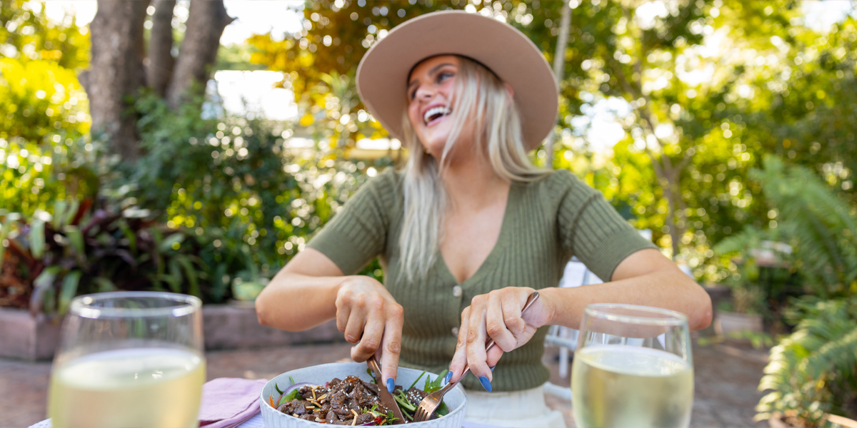 Young woman smiling as she enjoys a beef salad lunch.
