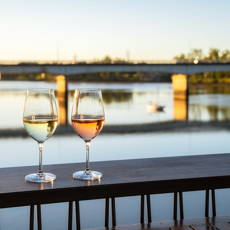 two wine glasses at a table overlooking the river