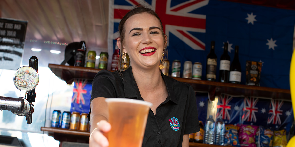 A lady pouring a beer with an Aussie flag in the background