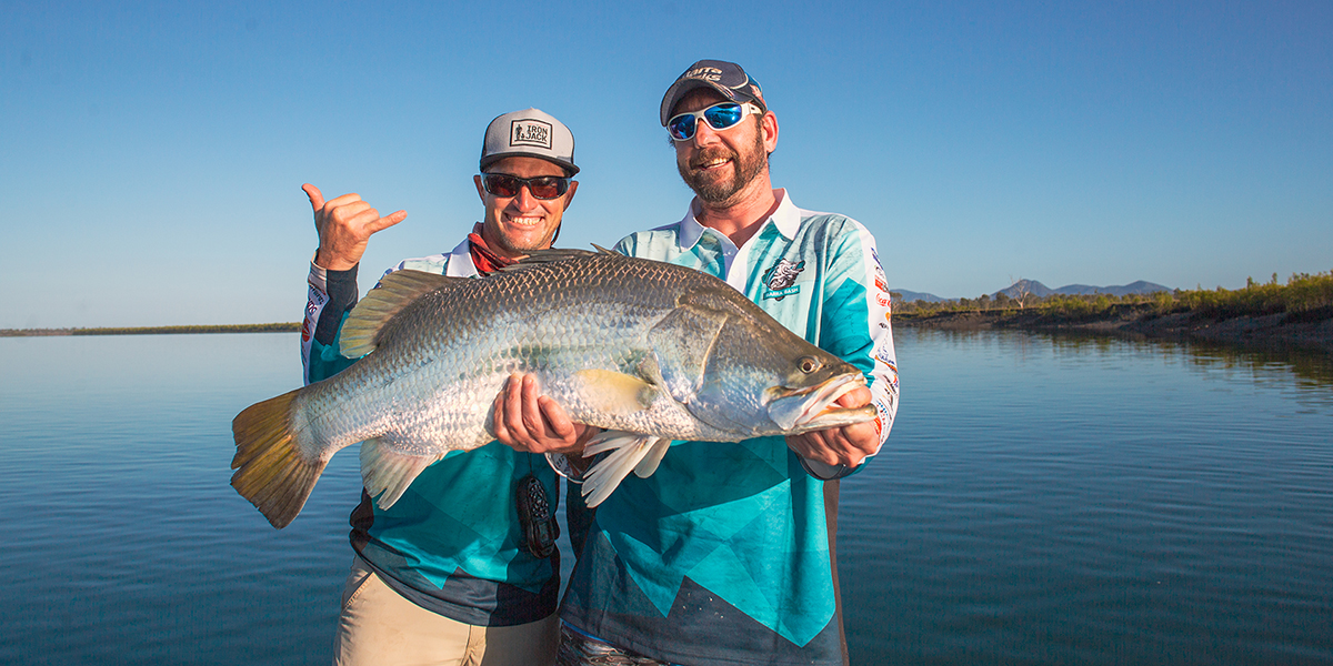 Two men celebrating catching a large barramundi in the Fitzroy River.