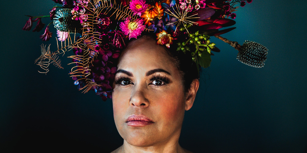 Photo of Australian music artists Christine Anu wearing a giant flower arrangement on her head.