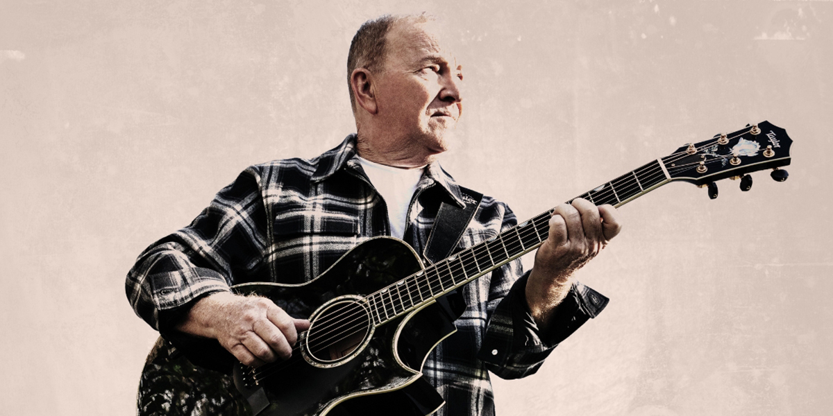 Man wearing a plaid shirt, playing guitar looking off to the right