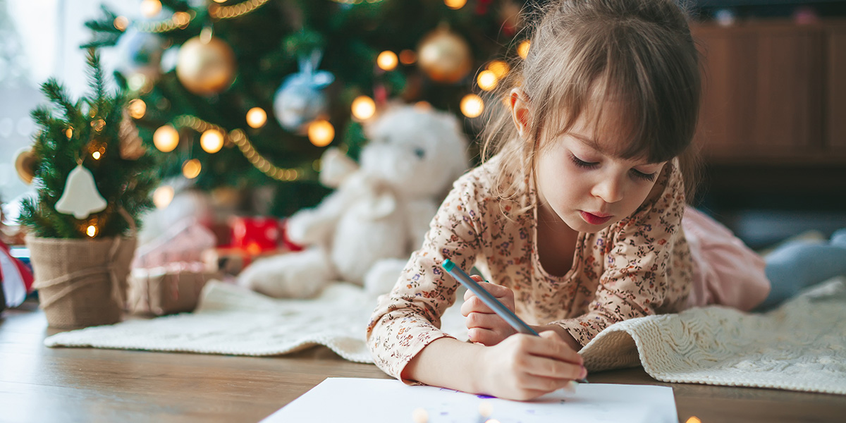 a girl laying on a bed writing a letter to Santa