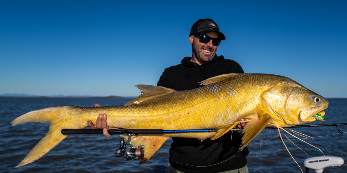 man smiling with glee whilst holding an enormous yellow king threadfin salmon fish