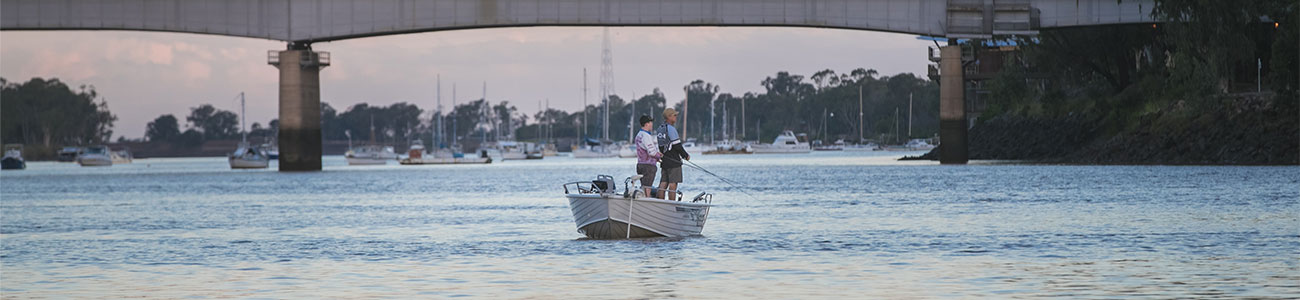 three people fishing from a boat on the river