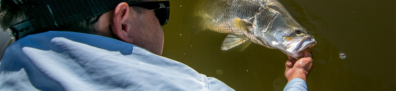 a man releasing a fish back in to the water