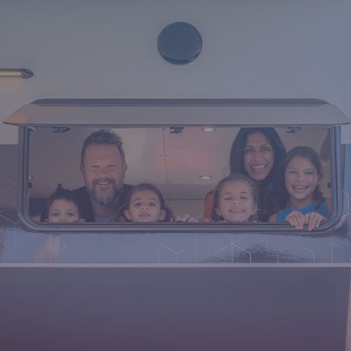 a ,am, woman, 3 young girls and a boy look through a caravan window
