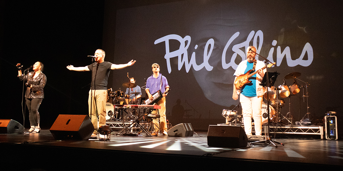 A Phil Collins tribute band playing music on stage.